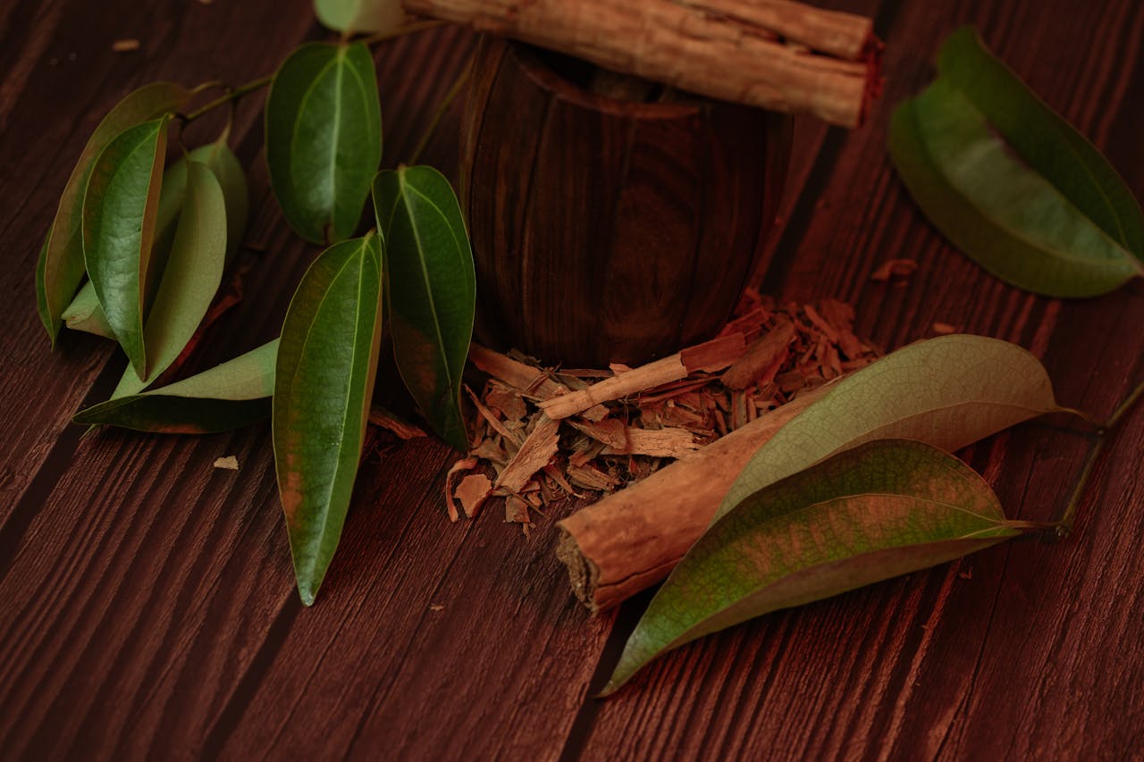 Cinnamon sticks and leaves on a wooden surface, highlighting their natural beauty.