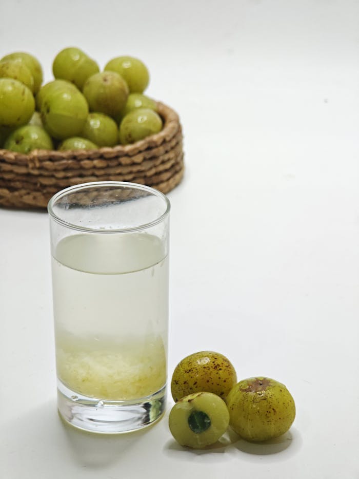 Glass of refreshing Indian gooseberry juice with fresh amla and a woven basket in the background.